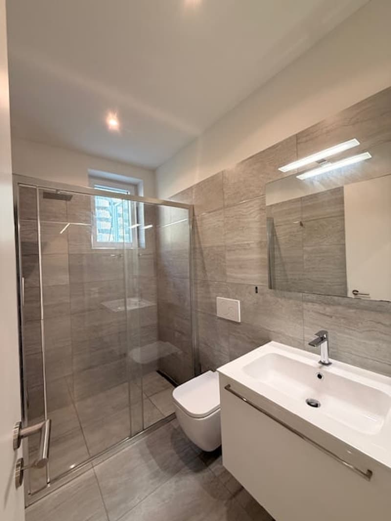 a modern bathroom with glass shower enclosure, white toilet, white sink, faucet, mirror, tiled floor, and recessed lighting