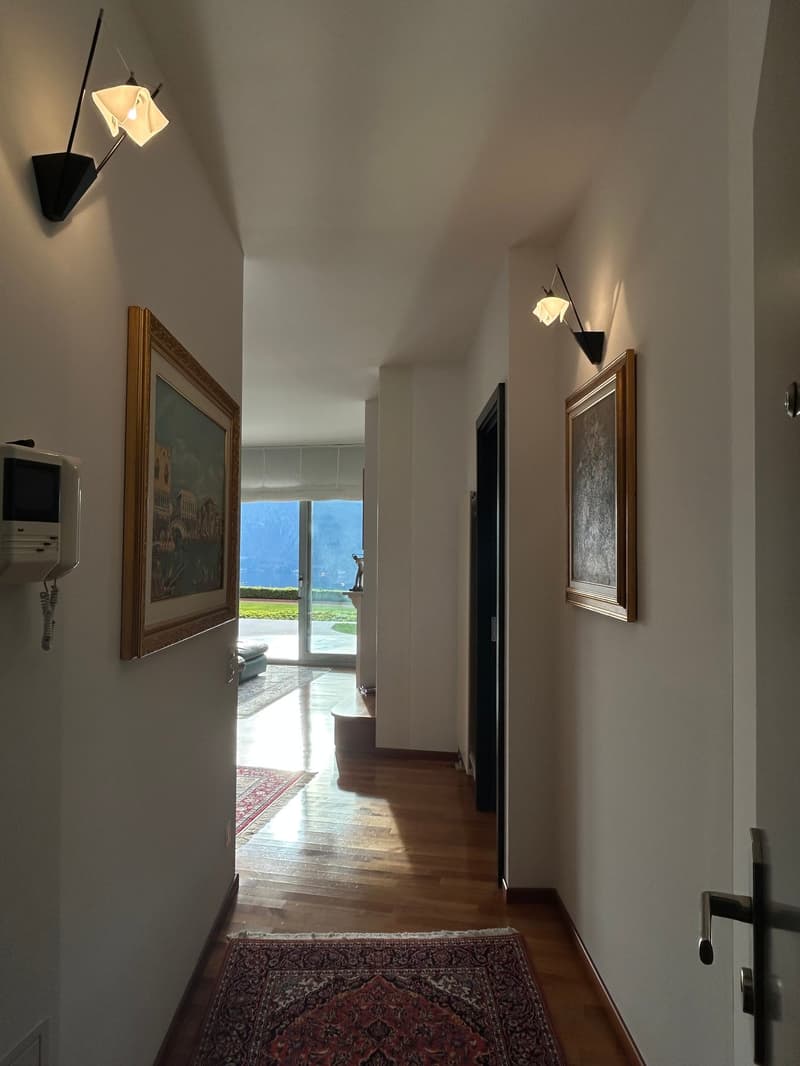 wooden floor, white walls, two picture frames, two wall lamps, rug, telephone, glass door, view of outside