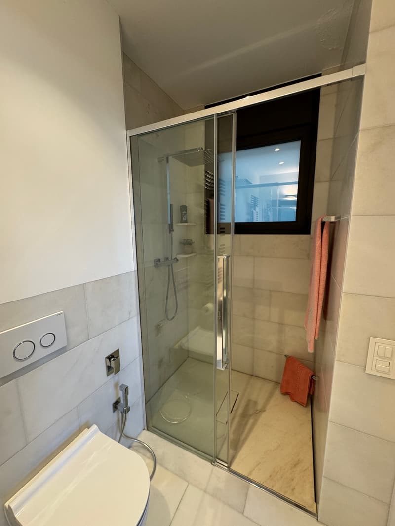 modern design bathroom, fully tiled, glass shower enclosure, no toiletries