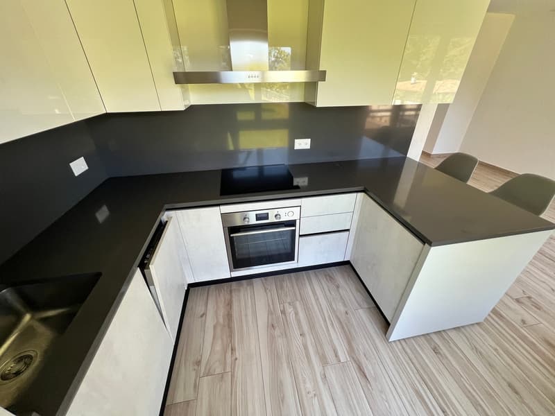 modern kitchen with black countertops, white cabinets, stainless steel appliances, wooden floor