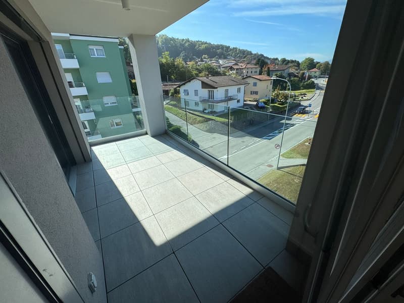 Balcony with glass railing, tiled floor, view of the street and houses