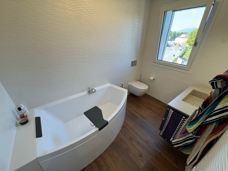 white bathtub, white sink, white toilet, wooden floor, window