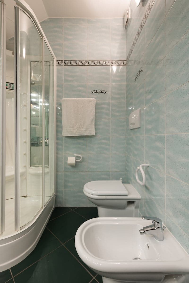 Bathroom with shower, toilet, sink, towel rack, and blue tiles
