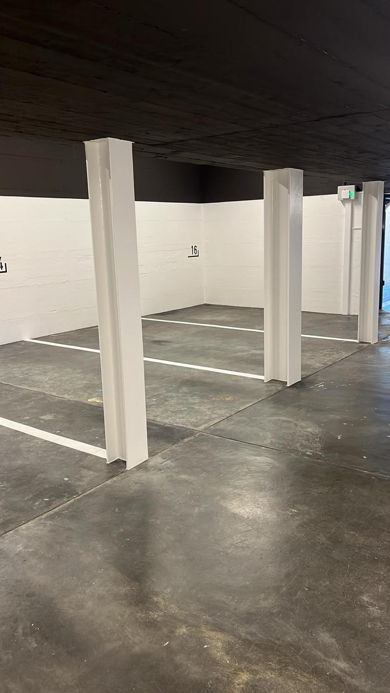 Empty parking lot with white walls, gray floor, and white pillars