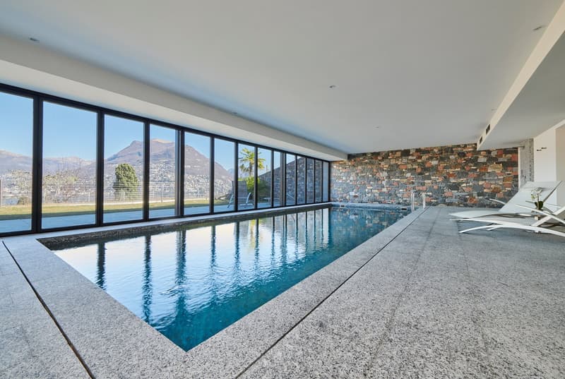 large indoor swimming pool, large windows, stone wall, lounge chairs, mountain view