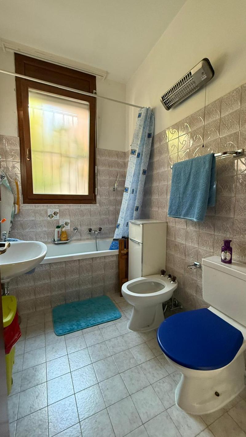 Bathroom: bathtub, two toilets, sink, cabinet, radiator, towels, mat, window, power outlet