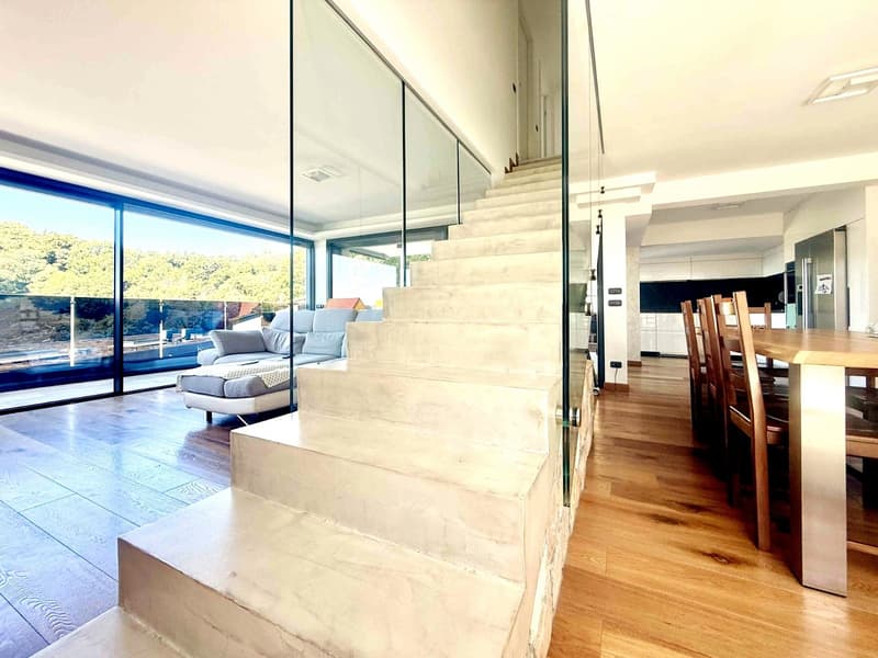 modern interior, large glass walls, white marble stairs, wooden floor, dining table, chairs, couch, kitchen