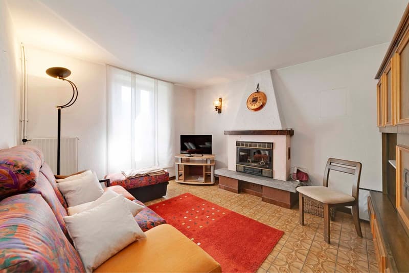 Couch, throw pillows, red rug, fireplace, TV, lamp, chair, shelves, clock