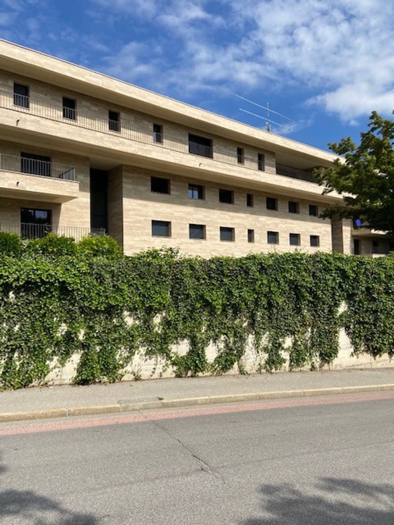 3 story building, beige exterior, multiple windows, balconies, ivy covered wall