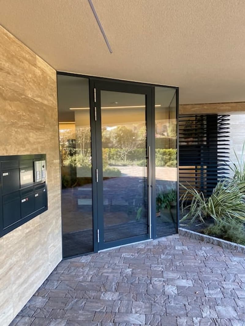 Entrance with glass doors, stone floor, mailbox, and plants