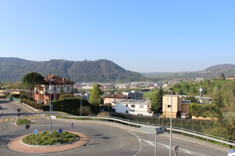 Aerial view of a town with buildings, mountains, and a road with a roundabout