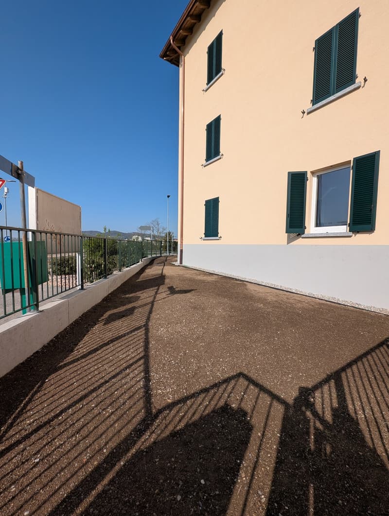 Building with beige walls, green shutters, and a paved walkway in front.