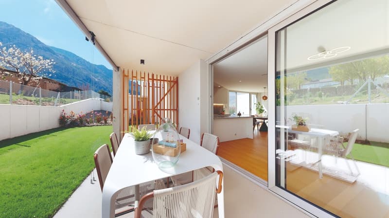 Dining area with a table and chairs, glass doors, wooden floor, plants, garden view