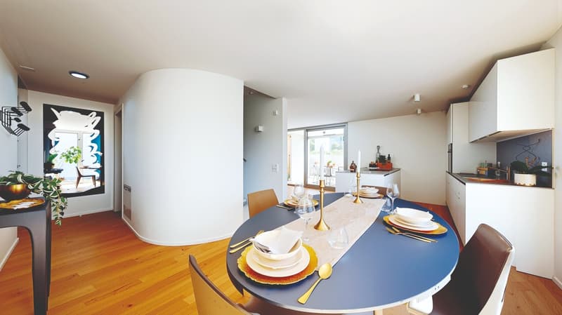 Dining room with a round table, chairs, and a white wall with a large painting. The room has wooden floors and a modern design.
