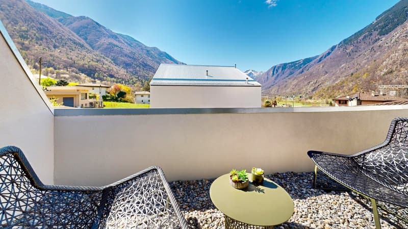 Balcony with pebble floor, two chairs, table with plants, mountain view