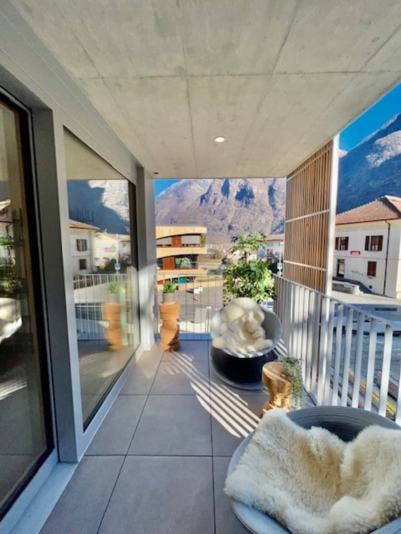 Balcony with outdoor seating, potted plants, and stunning mountain view.