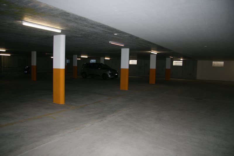 underground parking lot with pillars, car parked, fluorescent lights