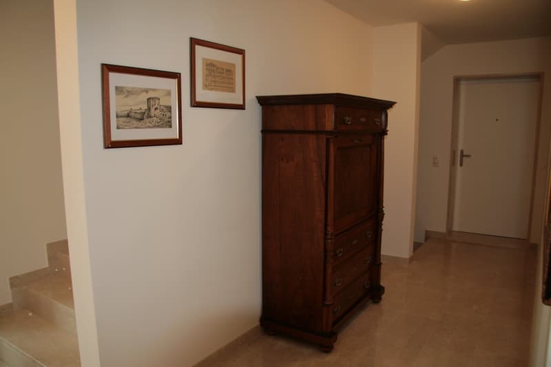 wooden cabinet, two framed pictures, white wall, tiled floor, door