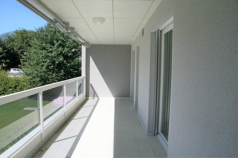 Balcony with white railings, tiled floor, glass railings, ceiling light, shadow on the floor