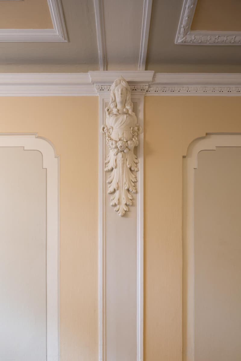 decorated ceiling, carved female statue, yellow and white walls