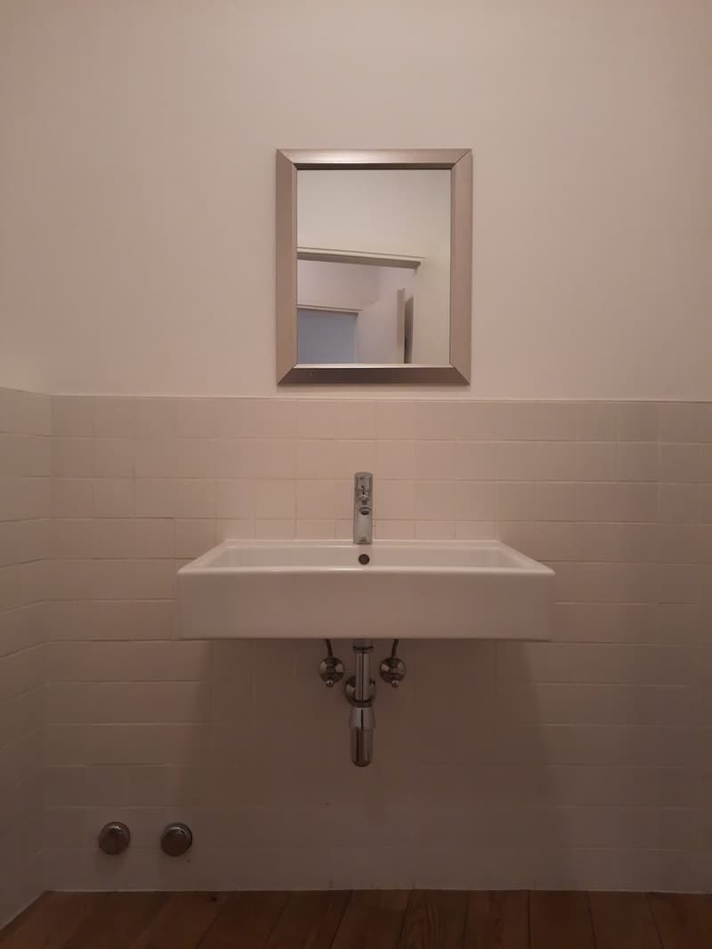 a small white sink mounted on the wall with a silver faucet