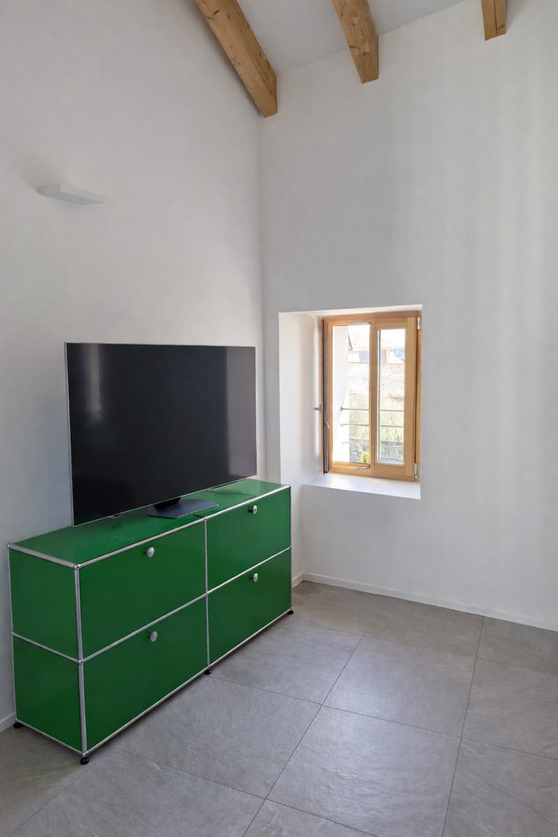empty room, white walls, tile floor, wooden beams on ceiling, green dresser, flat screen tv, window