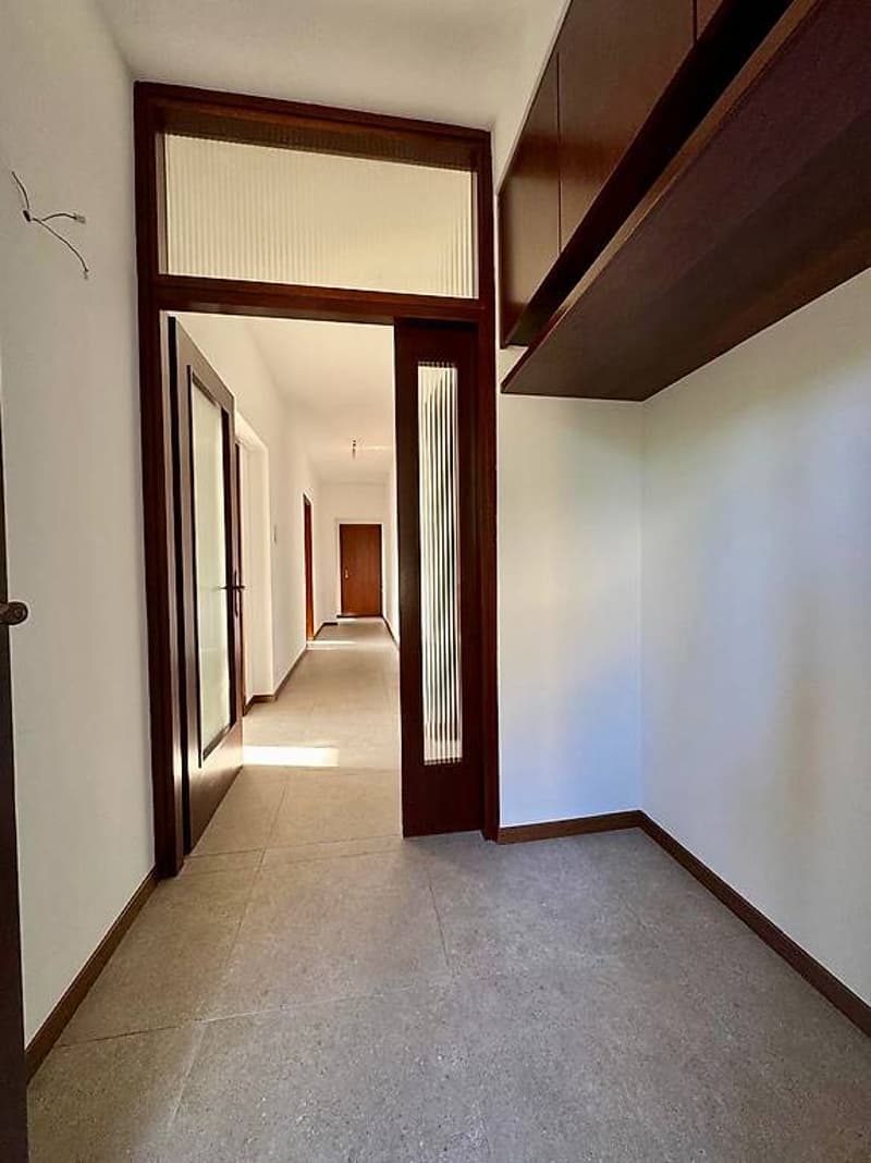 empty hallway with wooden doors and tiled floor