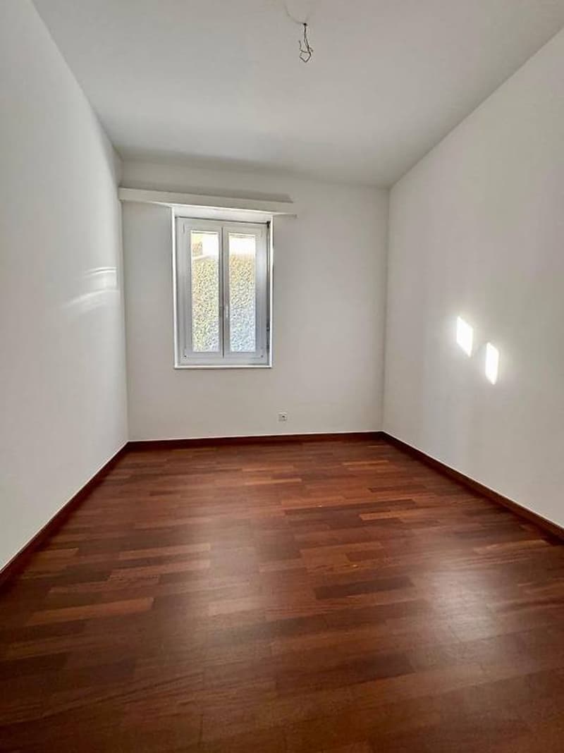 Empty room, hardwood floors, white walls, window, power outlet