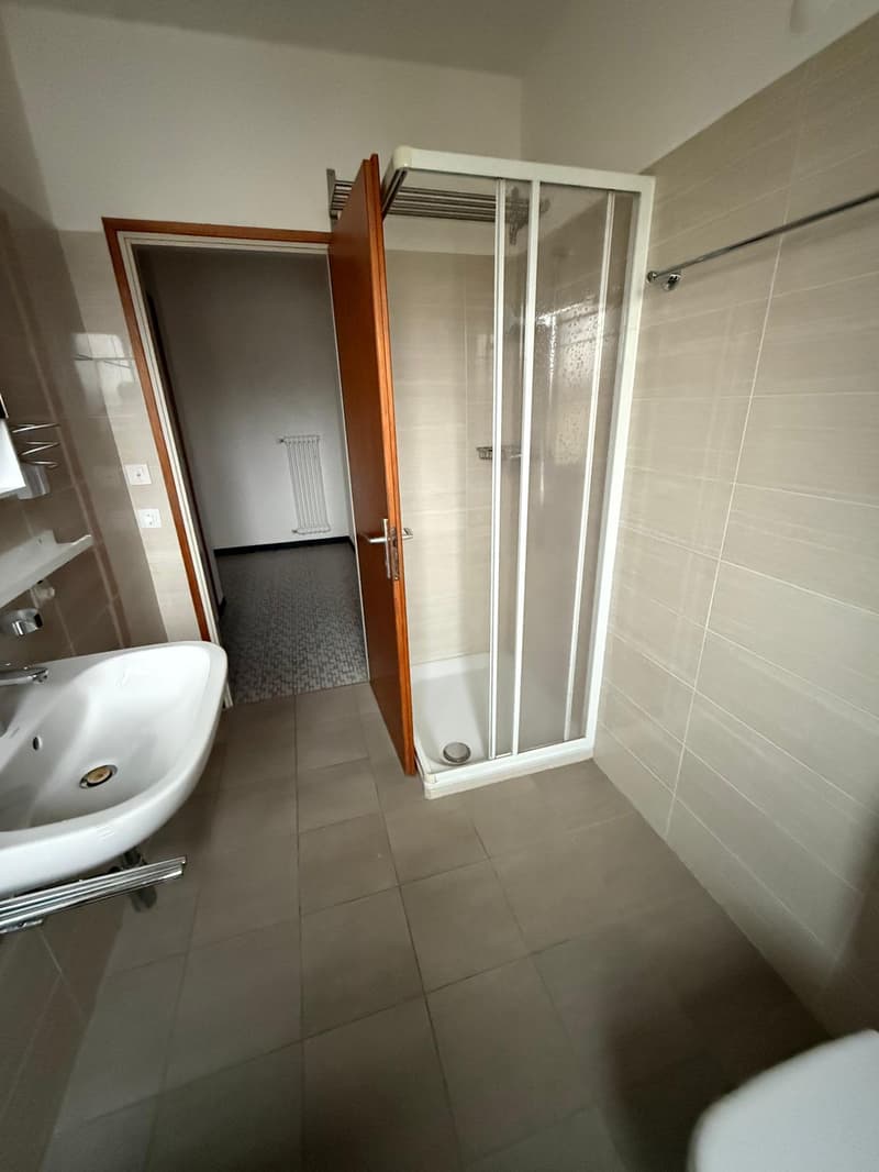 Bathroom with white sink, shower enclosure, and tiled flooring