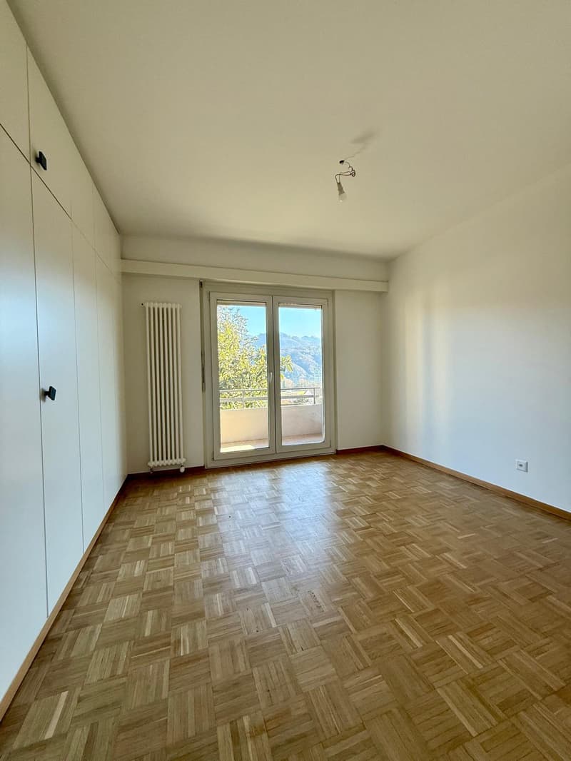modern room with wooden parquet flooring, sliding glass doors, white walls, built-in wardrobes, white radiator