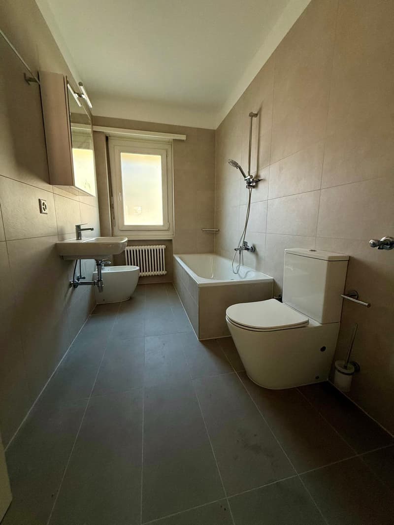 Tiled floor, white bathtub, toilet, sink, bidet, mirror, radiator, power outlet