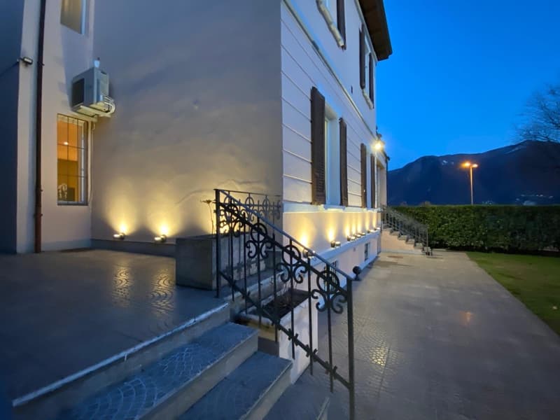 2 story white building, decorative stairs with wrought iron railings, night lighting