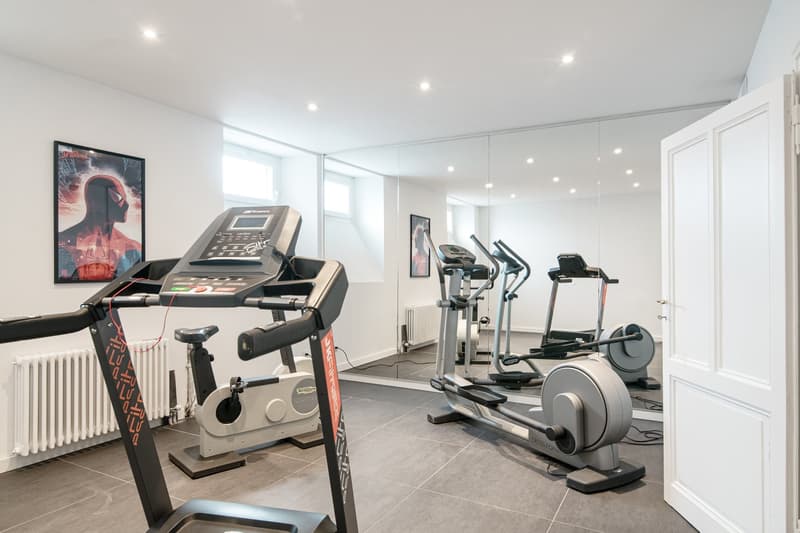 equipped with treadmill, elliptical, and strength training machines, white walls, and mirrors