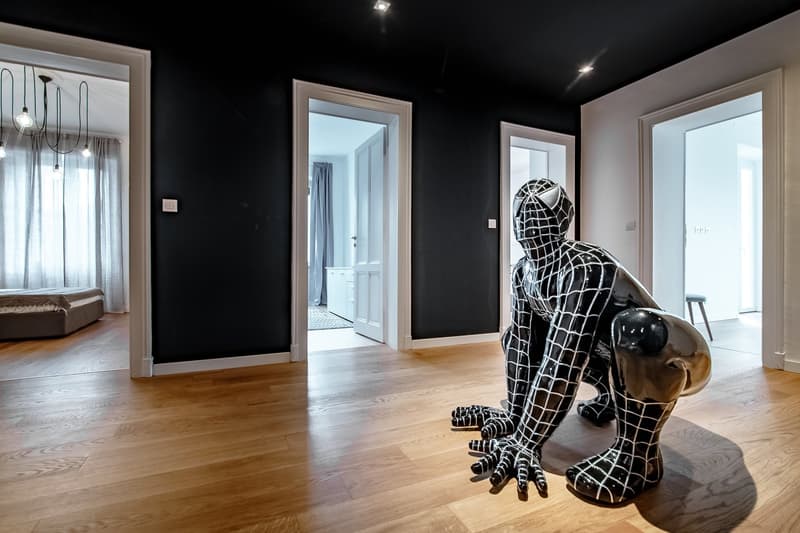 dark walls, wooden floor, decorative statue, doorways leading to other rooms