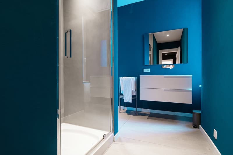 Shower, mirror, vanity, blue walls, white tiles, and towel rack