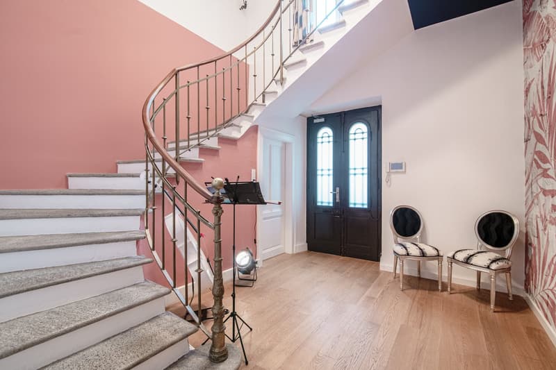 Marble staircase, hardwood floor, large double doors, two silver chairs, wall light