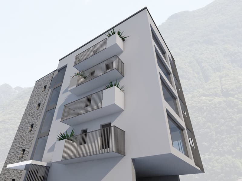 Modern multi-story apartment building with a sleek, angular design. The building features several balconies with metal railings and some greenery. The exterior is predominantly gray in color with a mix of smooth and textured surfaces.