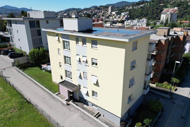 A multi-story building with a rooftop terrace and a garage entrance.
