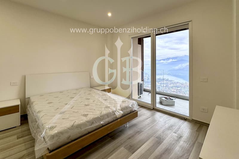 Sliding glass door leading to balcony, hardwood floors, single bed with mattress cover, white wall, city view