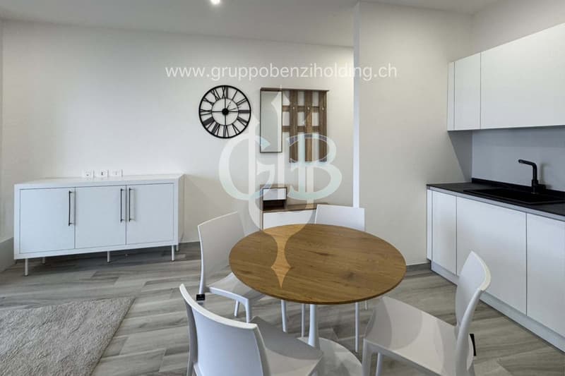 modern kitchen, round wooden table, white chairs, black countertop, wall clock, carpet, white cabinets