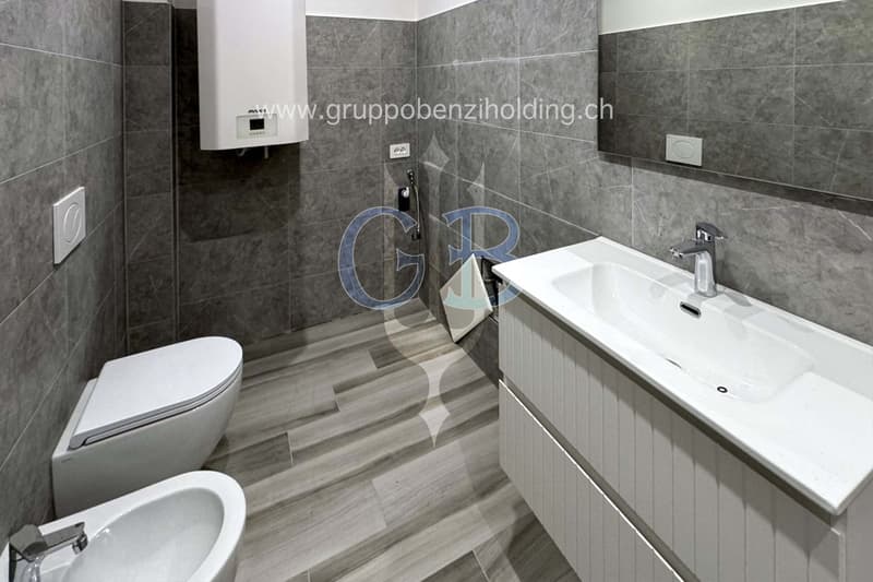 modern and minimalist bathroom with gray walls, white sink, white bidet, white toilet, wooden floor, modern shower head