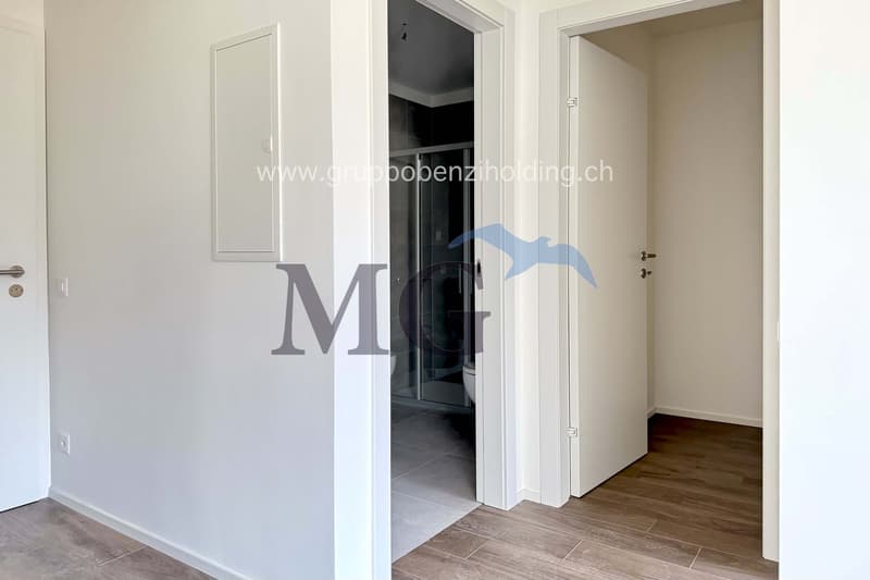 Empty room, white walls, wooden floors, interior door, white walls, shower room, washing machine visible