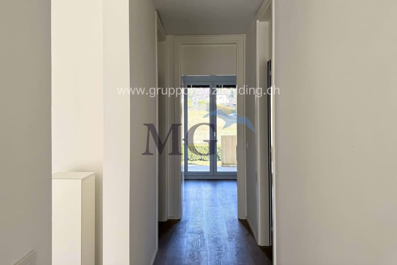 Long corridor, white walls, wooden floor, glass door, open balcony, outside view