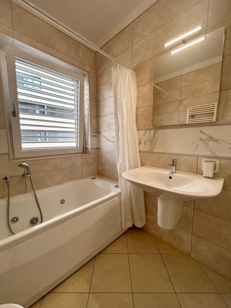 Bathroom with bathtub, sink, mirror, and window with blinds