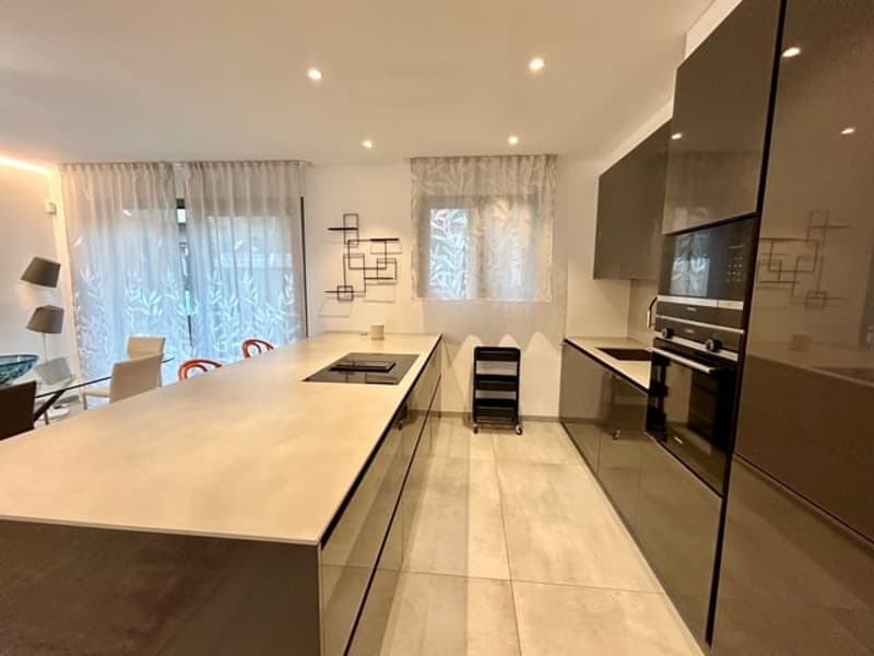 large kitchen island with hob and oven, granite countertop, built-in dishwasher and microwave, modern cabinets, ceiling spotlights