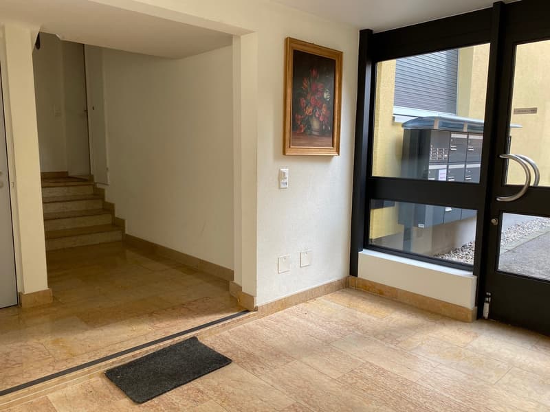 Tiled floor, white walls, steps leading to upper floor, picture frame, entrance door