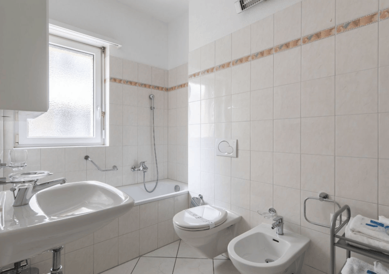 Bathroom with bathtub, sink, bidet, toilet, window, towels