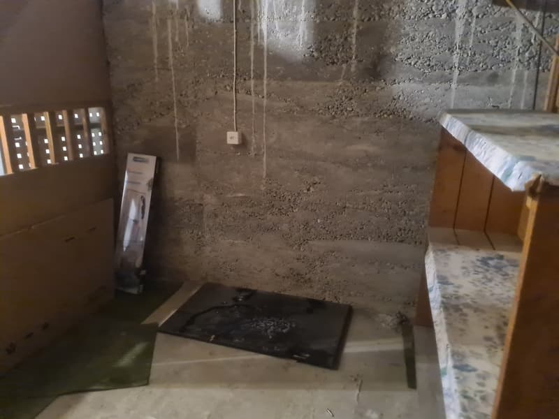 small room, dirt floor, dirty concrete wall, open doorway, exposed electrical wiring, dark black area