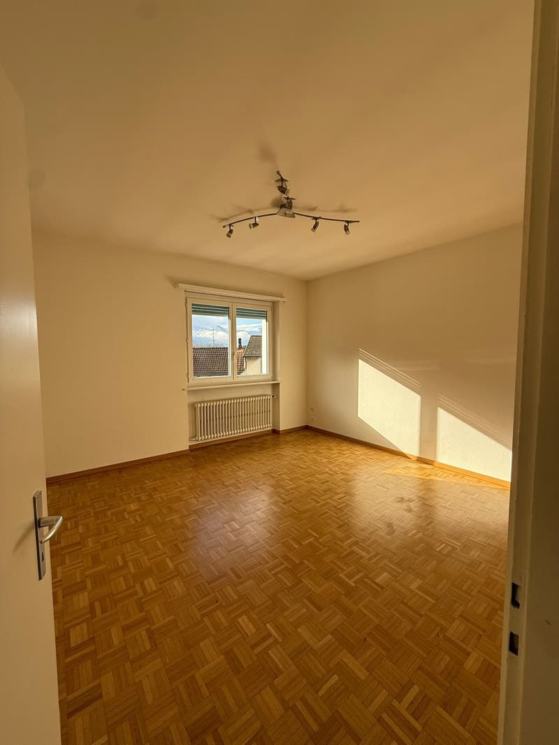large room with large window, white radiator, wooden floors, no furniture