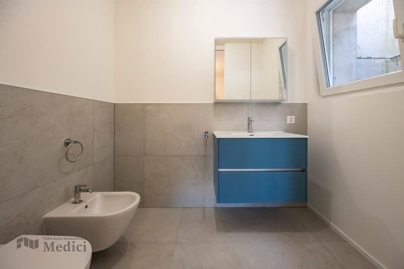 modern design, wall-mounted sink, mirror, recessed lights, white ceramic floors, blue cabinetry, power outlet